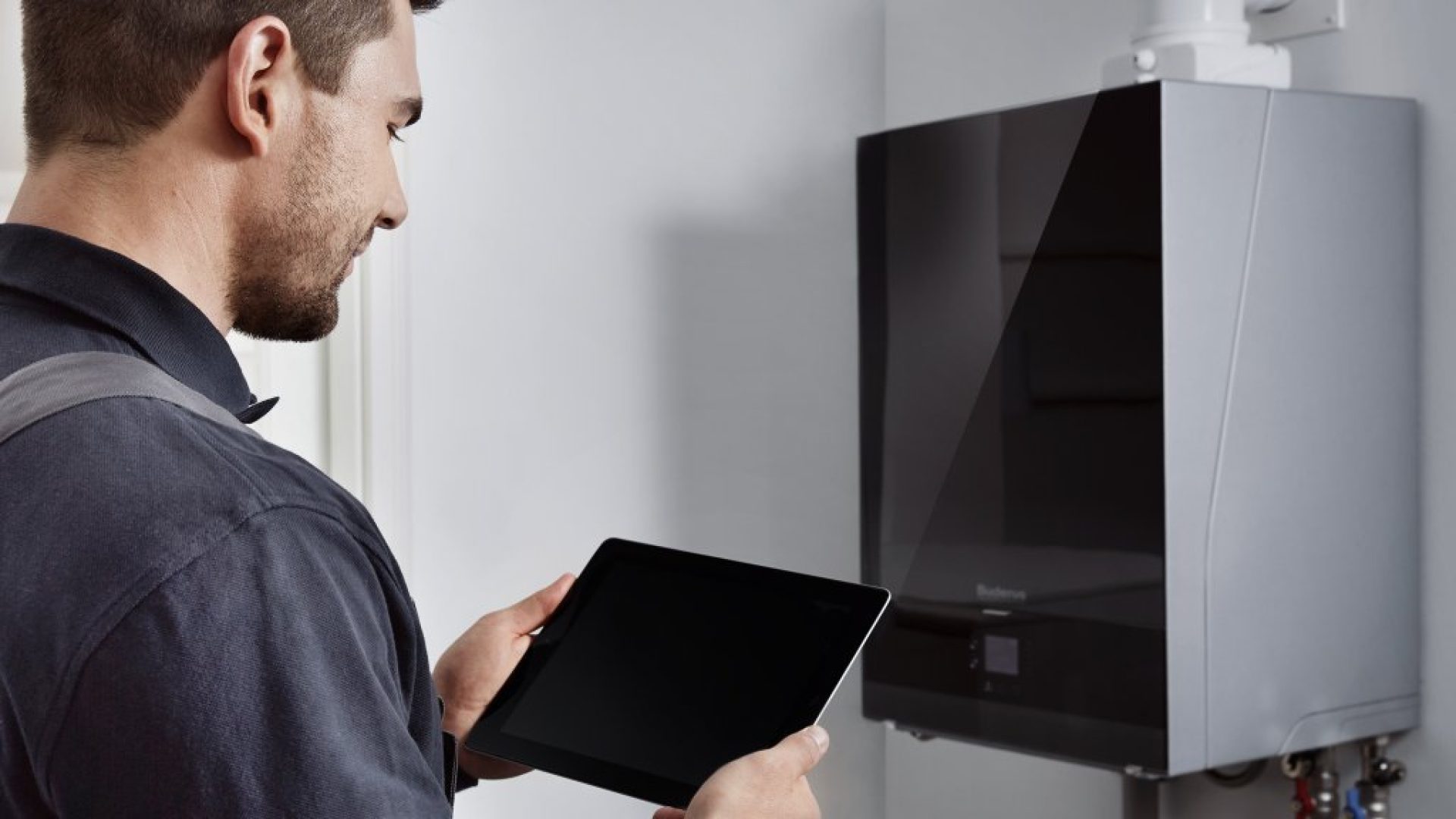 man_with_tablet_in_front_of_buderus_boiler_305478_1440x576
